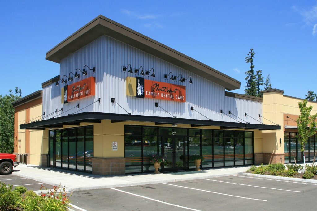 Modern dental office building with large windows and yellow/tan exterior in commercial setting.