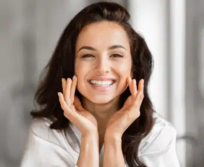 Woman smiling with hands to face in dental office setting, promoting dental care