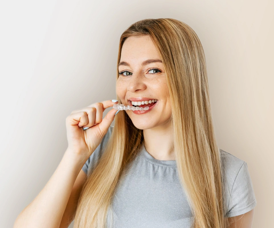 Young woman smiling while brushing teeth against white background, dental care concept.