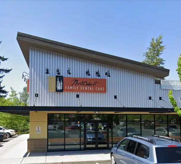 Modern dental office storefront with white corrugated siding and glass entrance, parked car visible.
